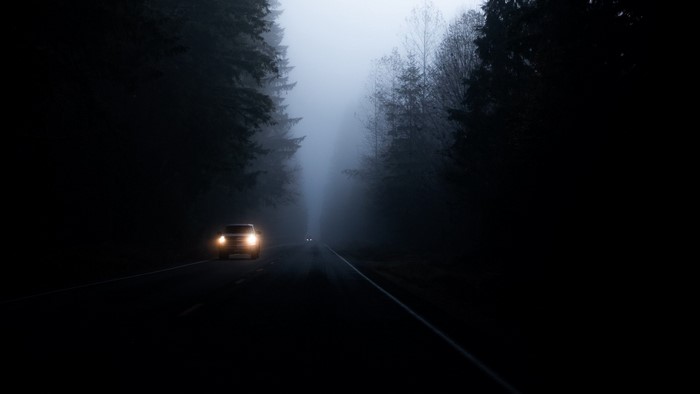 Car driving on a foggy road at night
