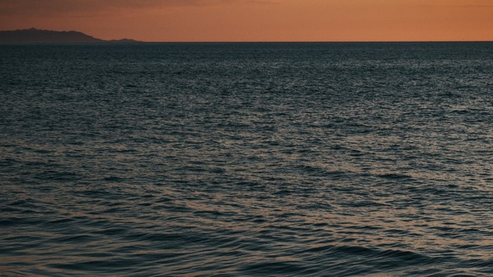 Ocean waves at sunset with distant mountains