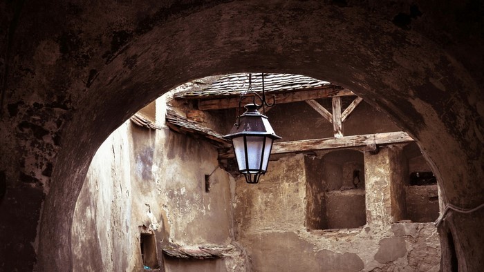 Old stone archway with hanging lantern and tiled roof