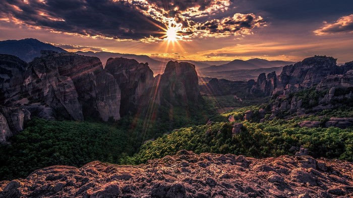 Sunset over Meteora rock formations with dramatic clouds