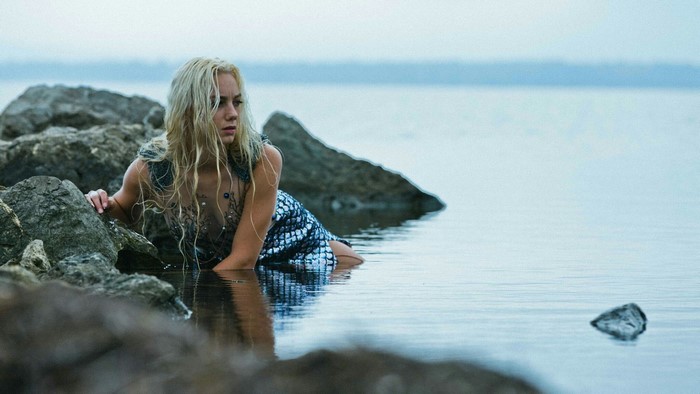 Woman in a mermaid costume on rocks by the water