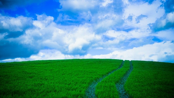 Green rolling hills under a cloudy blue sky
