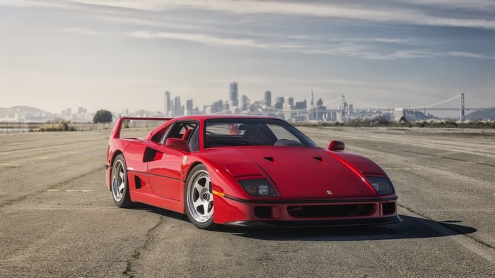 Red Ferrari F40 on asphalt with city skyline