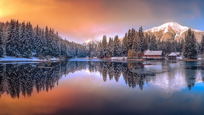 Winter lake with snow-covered trees and mountains