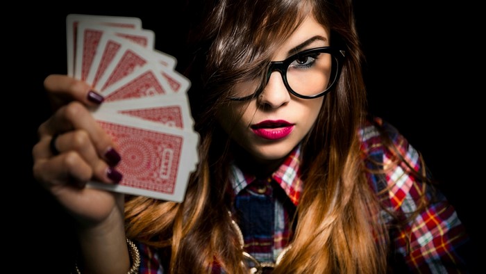 Woman in glasses holding playing cards