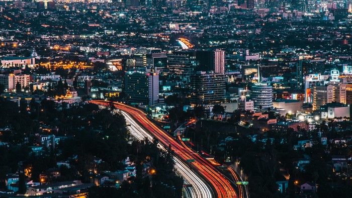 Nighttime cityscape with light trails on a highway
