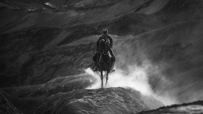 Rider on horseback in a dusty landscape