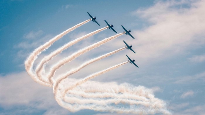 Five planes performing an aerial maneuver with smoke trails
