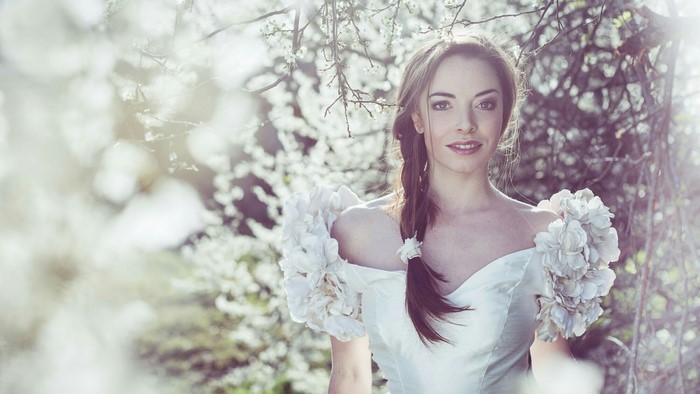 Woman in a white dress among blooming trees