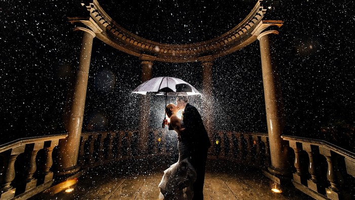 Couple kissing under umbrella in rain