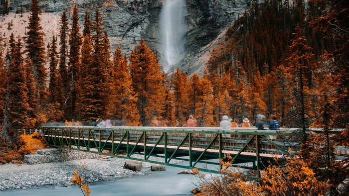 Bridge over river with waterfall and autumn trees