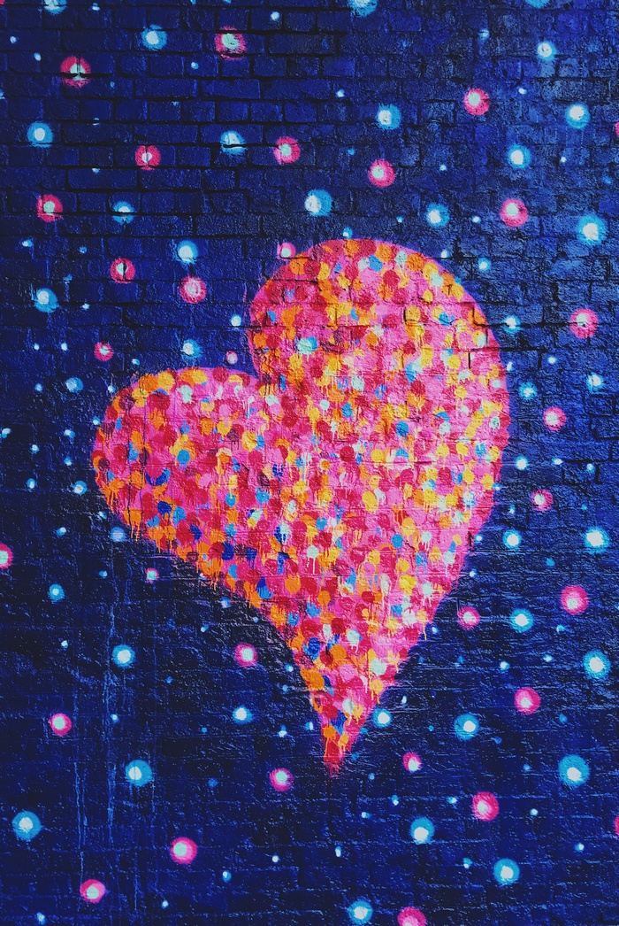 Graffiti heart with colorful dots on a brick wall