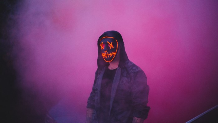 Person wearing a purge mask in pink smoke