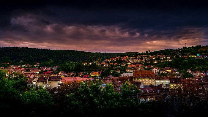 Cityscape at dusk with rolling hills