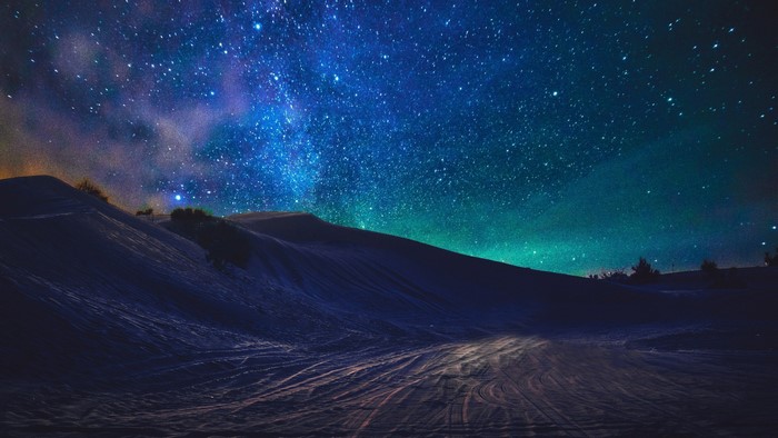Starry night sky over snowy dunes