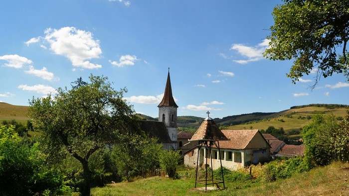 Village church with bell tower and surrounding hills