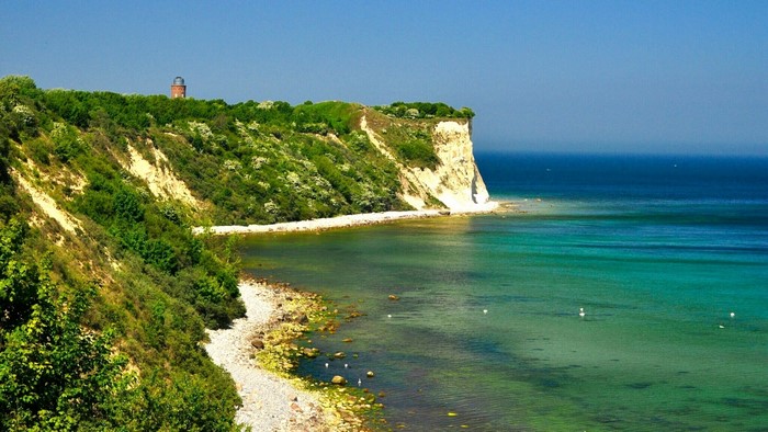 White chalk cliffs and turquoise sea with a lighthouse