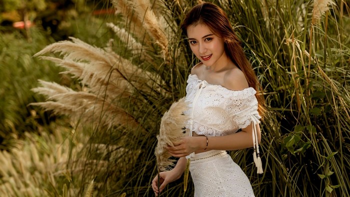 Young woman in white dress among tall grasses