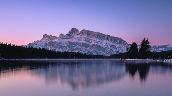 Snow-capped mountain reflected in a calm lake at dawn