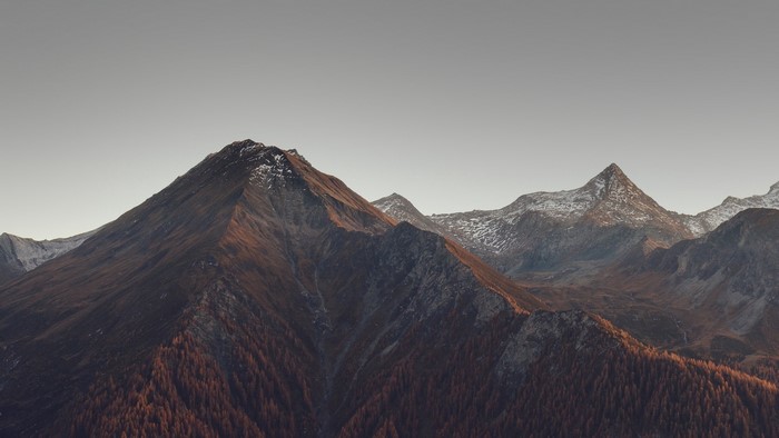 Mountain range with snow-capped peaks and autumn trees