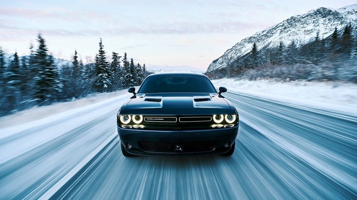 Dodge Challenger driving on a snowy mountain road