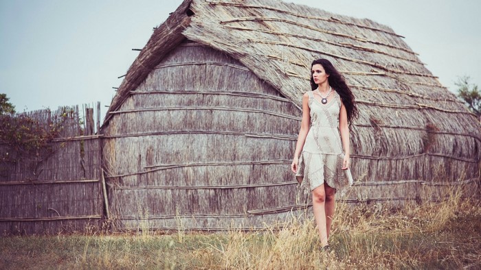 Woman in a dress near a thatched hut