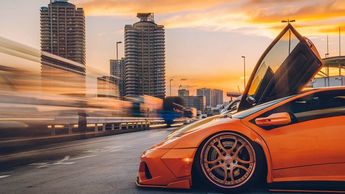 Orange Lamborghini Diablo with scissor doors at sunset