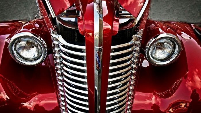 Close-up of a vintage red car grille and headlights