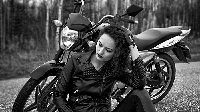Woman in leather jacket with motorcycle