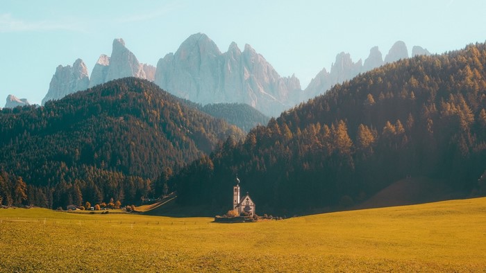 Church in a mountain valley with golden field