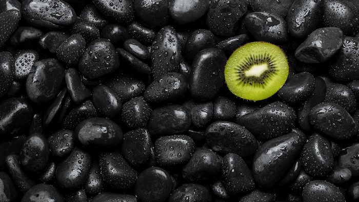 Slice of kiwi on black stones