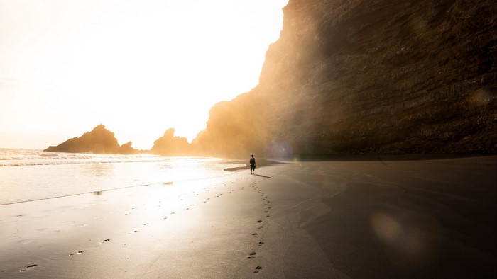 Person walking on a beach at sunset