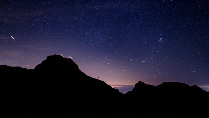 Starry night sky over silhouetted mountains