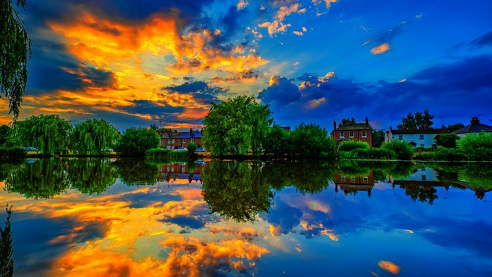 Sunset over a river with houses and trees