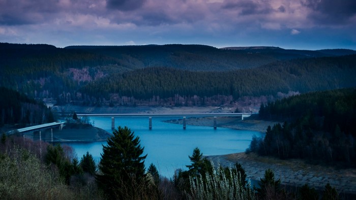 Bridge over a blue lake with forested hills