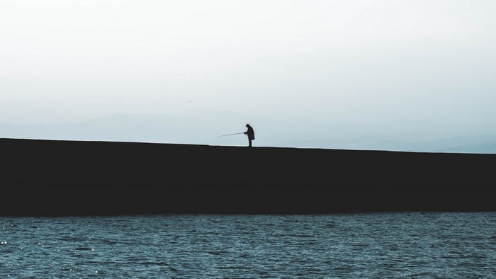 Fisherman on a wall by the sea