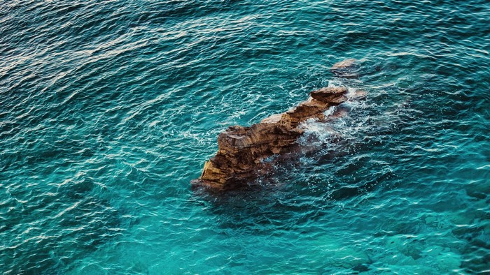 Rocky outcrop in turquoise ocean waves