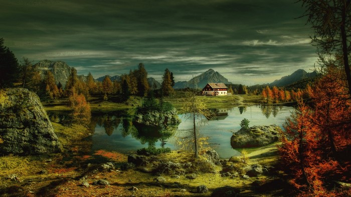 House by a lake with mountains and autumn trees