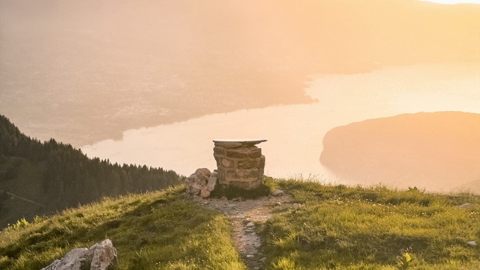 Stone structure on a grassy mountain peak overlooking a lake
