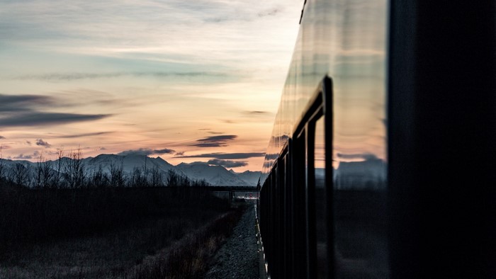 Train traveling through mountains at sunset