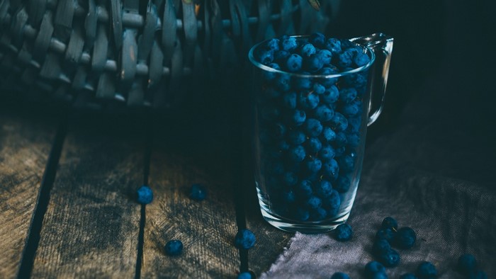 Blueberries in a glass pitcher on a wooden table