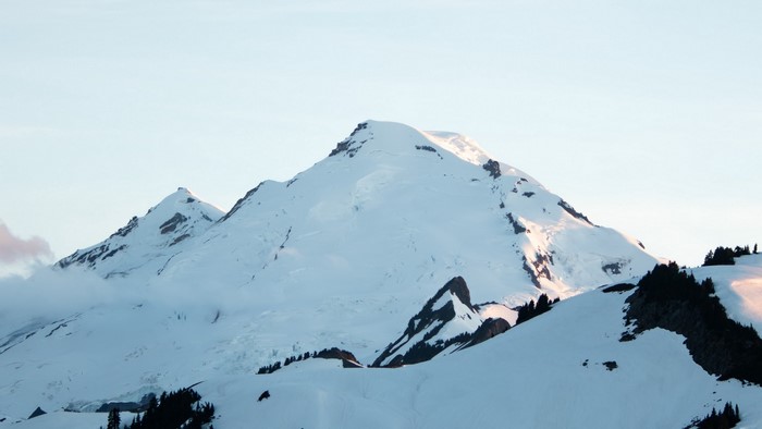 Snow-covered mountains under a pale sky