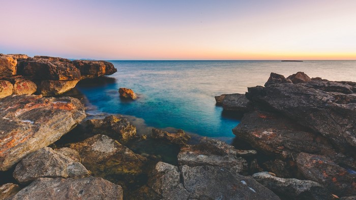 Rocky coast at sunset with calm ocean