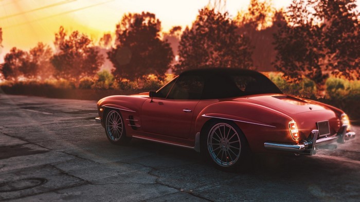 Red retro convertible car on a road at sunset