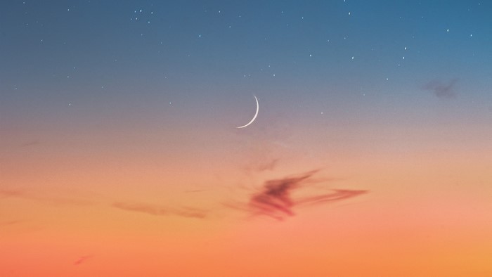 Crescent moon in a dusk sky with stars