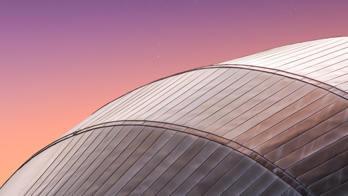 Curved metal roof against a gradient sky