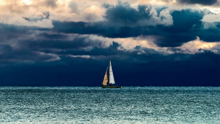 Sailboat on the sea under stormy clouds