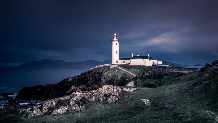 White lighthouse on a rocky cliff by the sea