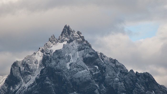 Snow-covered mountain peak under cloudy sky