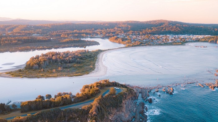Coastal landscape with river and town at sunset